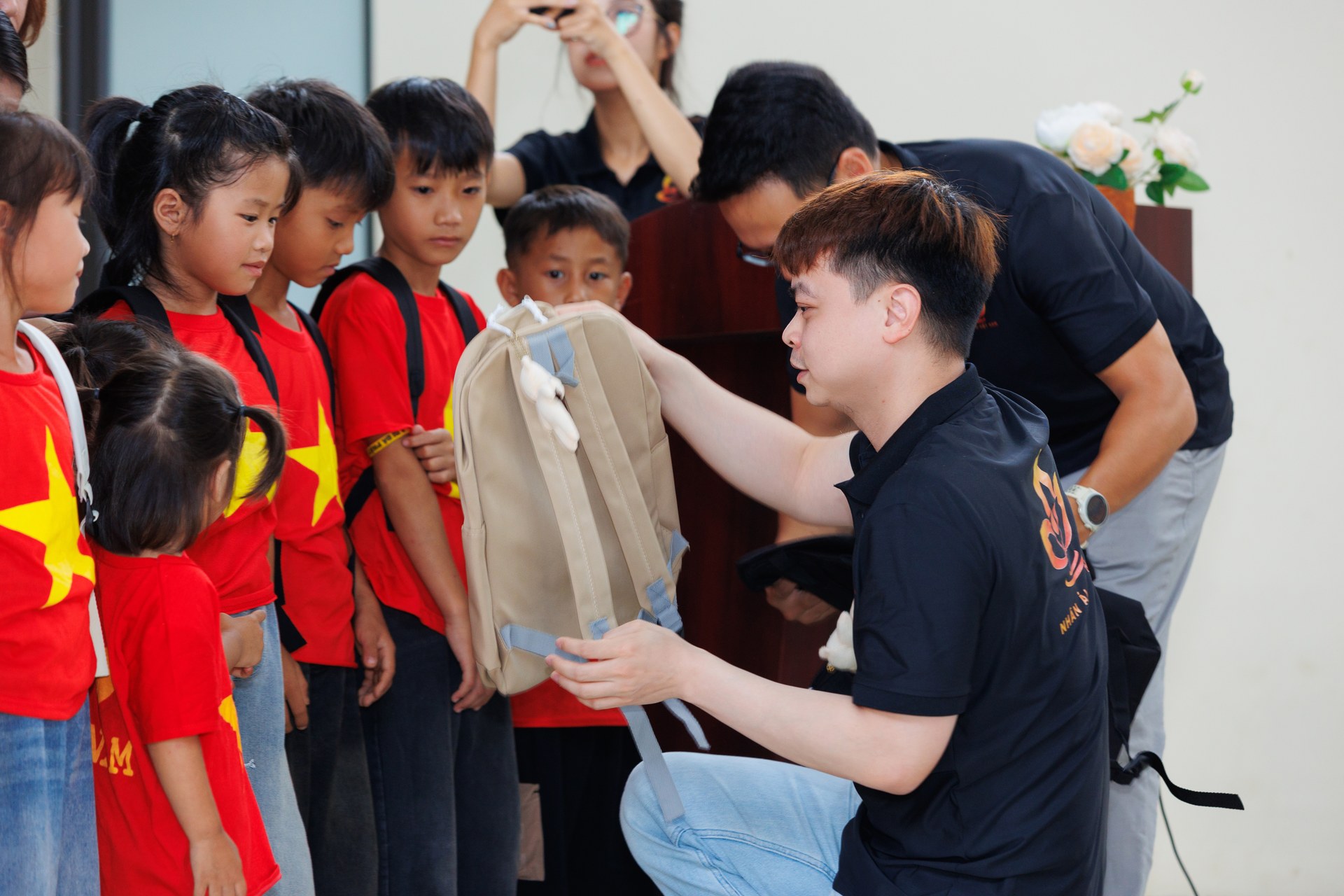 Thành viên Câu lạc bộ Nhân Ái Việt Nam trao cặp sách cho trẻ em